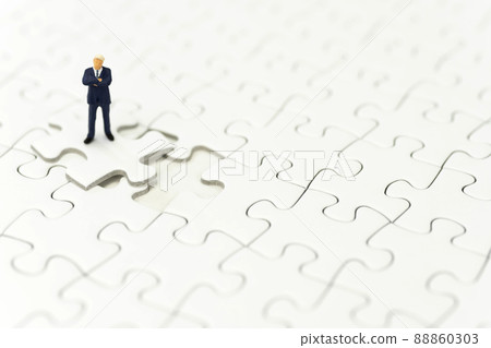 A businessman folding his arms on a jigsaw puzzle A businessman folding his arms on a jigsaw puzzle 88860303