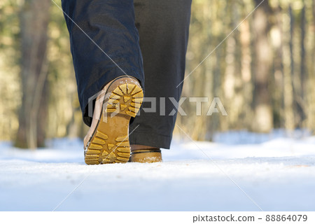 Woman walking on snow in winter forest. Focus on sole of show with snow. Woman walking on snow in winter forest. Focus on sole of show with snow. 88864079