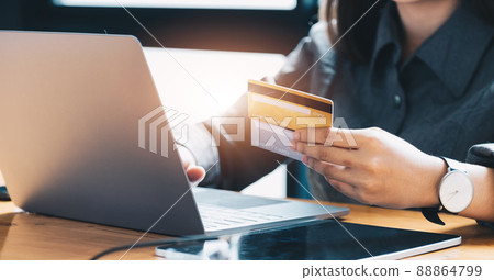 Young woman holding credit card and using laptop computer. Online shopping concept Young woman holding credit card and using laptop computer. Online shopping concept 88864799
