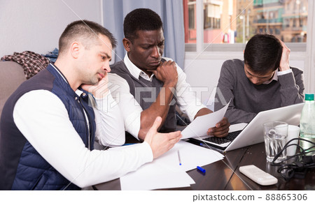 Three men are looking on documents and talking about it together Three men are looking on documents and talking about it together 88865306