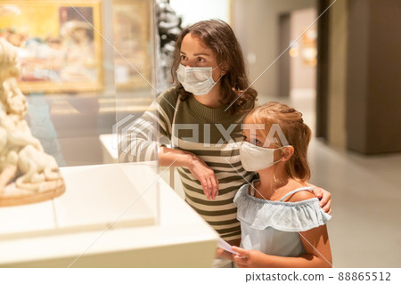 Girl with mother in masks looking with interest at art objects 88865512