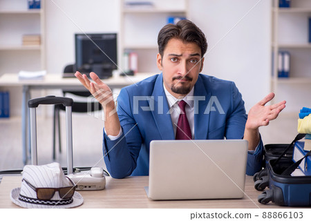 Young male employee preparing for trip at workplace Young male employee preparing for trip at workplace 88866103