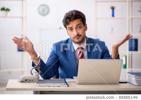 Handcuffed young male employee sitting in the office 88866146