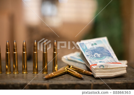 Sharp ammunition and a bundle of banknotes lie in a military box. 88866363