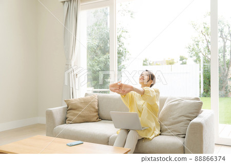 A woman who operates a personal computer, a sofa at home 88866374