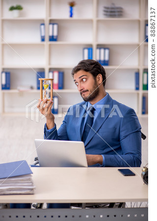 Young male employee in wheel-chair in time management concept Young male employee in wheel-chair in time management concept 88867137