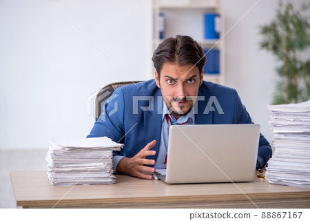 Young male employee and too much work in the office Young male employee and too much work in the office 88867167