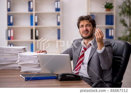 Young male employee unhappy with excessive work in the office 88867312