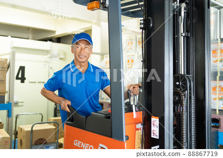 Middle male worker driving a forklift in a warehouse 88867719