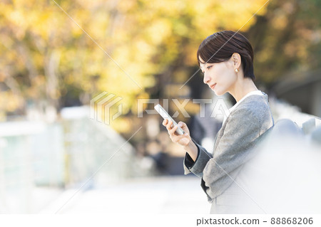 A woman operating a smartphone in the city 88868206