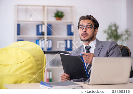 Young male employee looking after new born at workplace 88868316