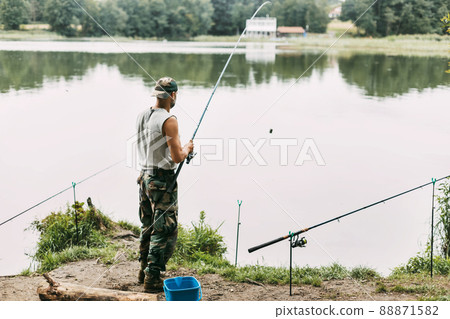 A young fisherman catches fish on a lake or river, prepares tackle and bait. Hobbies, weekends, fishing 88871582