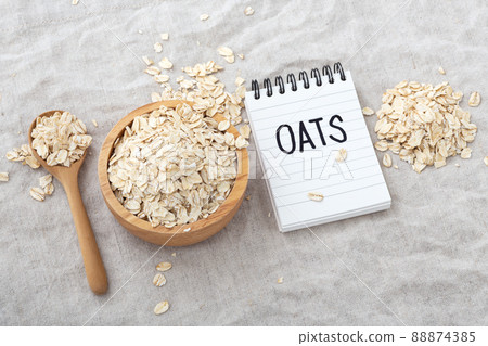 Oatmeal, oat cereal in wood bowl with oats word on notebook on linen cloth background 88874385