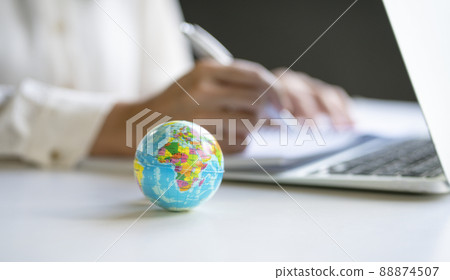 Close up view of world globe with businesswoman and computer laptop at the background. 88874507