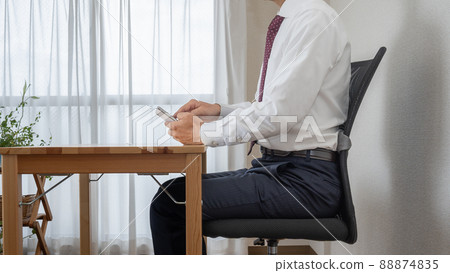A man who operates a smartphone in the correct posture. A businessman who works at home. 88874835