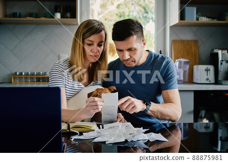 Man and woman checking payment bills in the kitchen at home. Planning family budget. Couple calculate bills and have stress 88875981