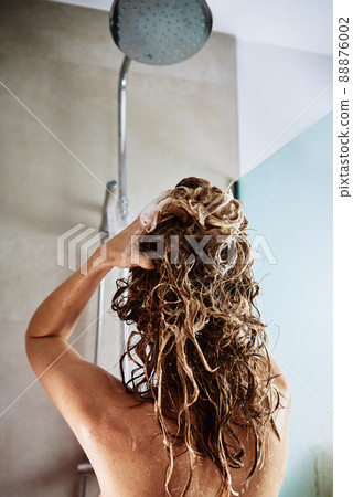 Woman standing under shower in bathroom cabin, washing her hair with shampoo Woman standing under shower in bathroom cabin, washing her hair with shampoo 88876002
