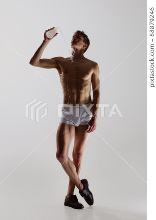 Full-length portrait of young handsome shirtless sportive man wearing white boxer-briefs moves smoothly isolated on white background. Wellness, fitness, beauty concept. 88879246