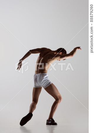 Contemp dance, performance. Young flexible shirtless man in underwear dancing isolated on gray background. Art, music, beauty. Healthy lifestyle concept Contemp dance, performance. Young flexible shirtless man in underwear dancing isolated on gray background. Art, music, beauty. Healthy lifestyle concept 88879260