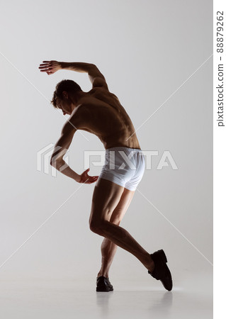Contemp dance, performance. Young flexible shirtless man in underwear dancing isolated on gray background. Art, music, beauty. Healthy lifestyle concept Contemp dance, performance. Young flexible shirtless man in underwear dancing isolated on gray background. Art, music, beauty. Healthy lifestyle concept 88879262