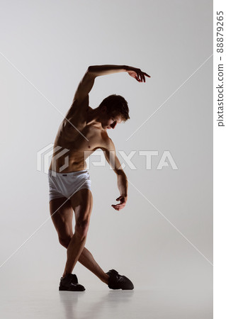 Contemp dance, performance. Young flexible shirtless man in underwear dancing isolated on gray background. Art, music, beauty. Healthy lifestyle concept Contemp dance, performance. Young flexible shirtless man in underwear dancing isolated on gray background. Art, music, beauty. Healthy lifestyle concept 88879265