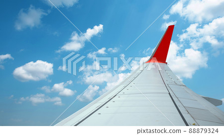 The wings of an airplane flying above the clouds. 88879324