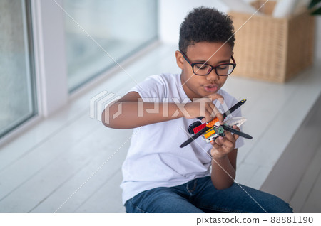 A boy in eyeglasses playing with a toy helicopter A boy in eyeglasses playing with a toy helicopter 88881190