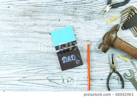 Vintage metal tools, the inscription dad in a notebook and a pencil, on a wooden background, top view, save space, the concept of congratulations on Father's Day, congratulations, postcard Vintage metal tools, the inscription dad in a notebook and a pencil, on a wooden background, top view, save space, the concept of congratulations on Father's Day, congratulations, postcard 88882061