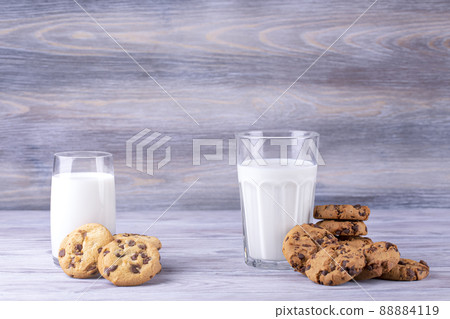 A stack of chocolate chip cookies lies near a glass of milk. Calcium-rich milk. 88884119