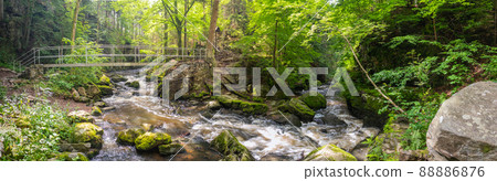 Doubrava wild river with an iron footbridge, in the woods, with rapids and rocks, near Chotebor, Czech republic 88886876