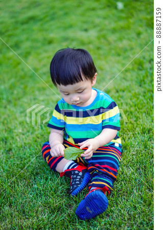 Kid sit thoughtful on the grass with idea space. Kid sit thoughtful on the grass with idea space. 88887159