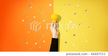 Person holding a yellow light bulb with stars 88887553
