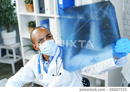 Male doctor examines an x-ray of lungs in hospital Male doctor examines an x-ray of lungs in hospital 88887555