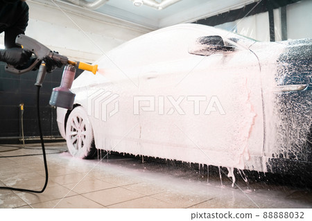Car wash employee applies foam to the car. Professional auto wash Car wash employee applies foam to the car. Professional auto wash 88888032