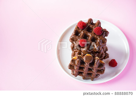 Stack of chocolate waffles with berries. Close up and pink background. 88888070