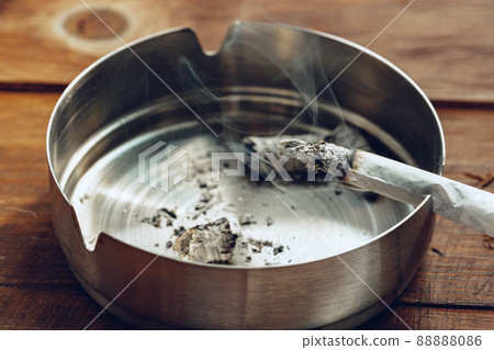 Lighted cigarette in a metal ash tray close up Lighted cigarette in a metal ash tray close up 88888086