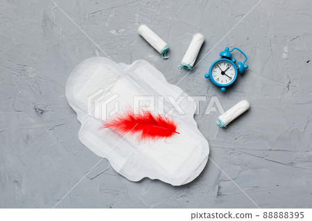 Ringing alarm clock with sanitary female tampons and menstrual sanitary pads. Medical concept of woman critical days and menstruation. Female daily hygiene. Copy space Ringing alarm clock with sanitary female tampons and menstrual sanitary pads. Medical concept of woman critical days and menstruation. Female daily hygiene. Copy space 88888395