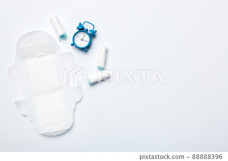 Ringing alarm clock with sanitary female tampons and menstrual sanitary pads. Medical concept of woman critical days and menstruation. Female daily hygiene. Copy space Ringing alarm clock with sanitary female tampons and menstrual sanitary pads. Medical concept of woman critical days and menstruation. Female daily hygiene. Copy space 88888396