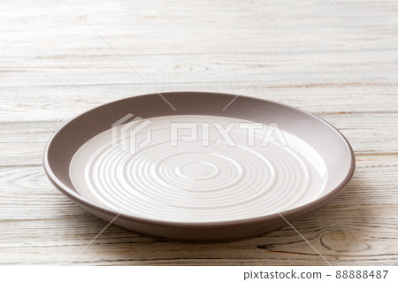 Perspective view of empty light plate on wooden background. Empty space for your design Perspective view of empty light plate on wooden background. Empty space for your design 88888487