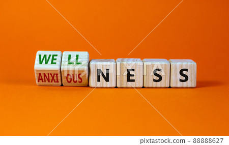 Wellness or anxiousness. Turned cubes and changed the word 'anxiousness' to 'wellness'. Beautiful orange table, orange background. Psychological, wellness or anxiousness concept. Copy space. 88888627