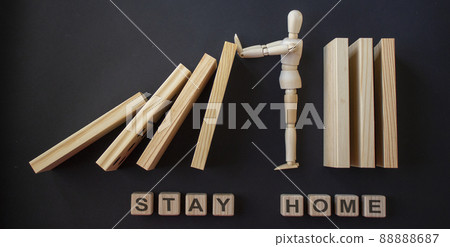 COVID-19 Pandemic Coronavirus concept. Wooden model of man stopping wooden domino blocks. Inscription on wooden blocks "stay home". COVID-19 Pandemic Coronavirus concept. Wooden model of man stopping wooden domino blocks. Inscription on wooden blocks "stay home". 88888687
