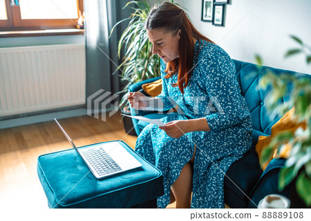 beautiful serious woman using laptop paying bills online and managing home budget beautiful serious woman using laptop paying bills online and managing home budget 88889108