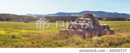 stack of straw bales on field of grass, landscape with meadow, pond, forest and hills in background stack of straw bales on field of grass, landscape with meadow, pond, forest and hills in background 88889537