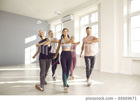 Group of happy young people doing sports exercises together while training in fitness studio. Group of happy young people doing sports exercises together while training in fitness studio. 88889671