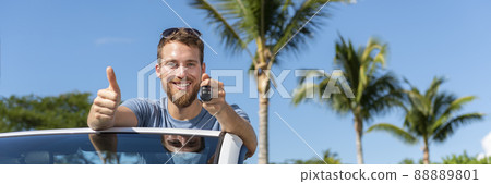 Car key new young owner driver man showing keys and thumbs up happy for new convertible buy or sell used cars. Driver's license concept with driving cabriolet on road trip banner panoramic 88889801