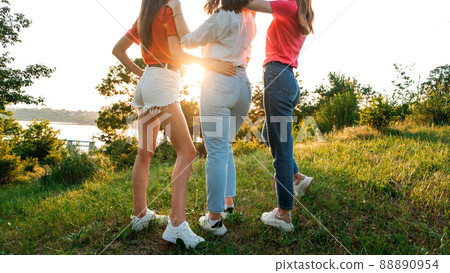 Group of girl friends jumping outdoors on sunset nature. Young multi-ethnic hipster friends dancing at summer party. Group of women friends hugging and ejoying the sunset in outdoor nature Group of girl friends jumping outdoors on sunset nature. Young multi-ethnic hipster friends dancing at summer party. Group of women friends hugging and ejoying the sunset in outdoor nature 88890954