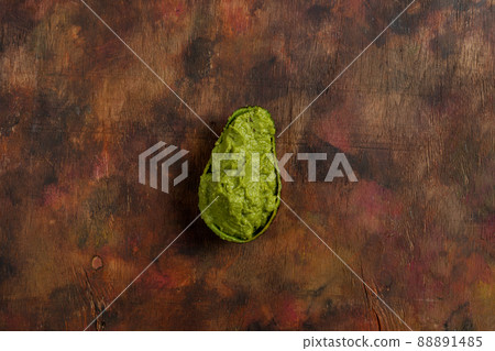 Top view of an avocado cut in half and filled with the tasty guacamole sauce on a wooden background in brown tones Top view of an avocado cut in half and filled with the tasty guacamole sauce on a wooden background in brown tones 88891485