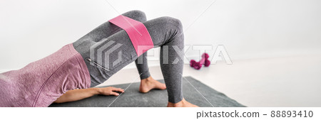 Fitness resistance band glute bridge with hip abduction exercise woman workout at home. Fit girl training with circle hoop booty bands for glute strengthening banner panorama 88893410