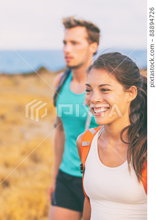 Happy young people walking on nature hike outdoors. Smiling Asian woman hiking hikers tourists with backpacks in summer travel 88894726