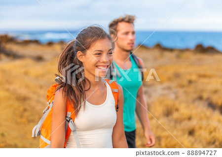 Happy young couple tourists in love holding hands walking on trek hike with backpacks. Hikers on nature travel hiker trail destination smiling happy. Interracial relationship 88894727